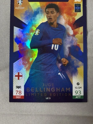 Jude Bellingham Limited Edition kort - Samlarkort från Topps Match Attax UEFA Euro 2024 med Jude Bellingham i Englands blå matchtröja. Kortet är en Limited Edition med holografisk bakgrund, spelarens namn i guldtext och statistik på framsidan. Baksidan har turneringslogga och England-emblem. Köparen står för frakten.
