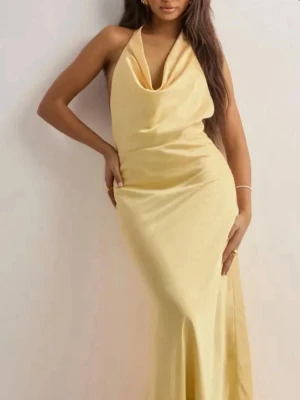 Halter Bow Dress - Balklänning  - Säljer en ny och oanvänd bal/fest klänning från Nelly.com. Med etikett kvar! Storlek 34. Ljusgul färg i satin. Slutsåld!! Köpt förra året men aldrig kommit till användning. 