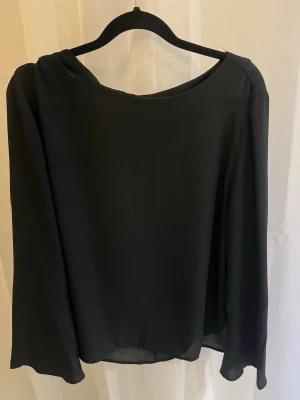 Svart långärmad blus med vid ärm - Svart blus med rund halsringning och långa, vida ärmar. 