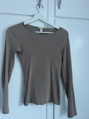 Beige ribbad långärmad topp H&M - Säljer en enkel och stilren beige långärmad topp från H&M. Toppen är ribbad och har en rund halsringning. Perfekt att matcha med jeans eller kjol för en clean look.
