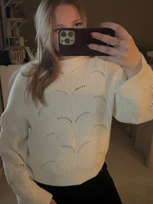 Vit stickad tröja med hålmönster - Säljer en vit stickad tröja med snyggt hålmönster och bred ribbad krage. Tröjan har långärmade ärmar och en loose passform som ger en chill vibe.