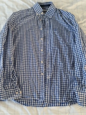 Blårutig skjorta från Marc O' Polo - Klassisk blårutig skjorta med lång ärm och knappar framtill. Skjortan har button-down krage och en bröstficka. Perfekt för en stilren och avslappnad look.