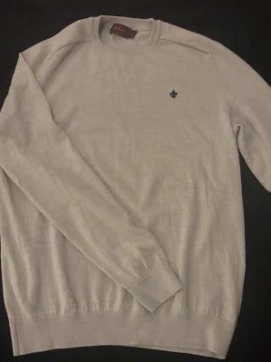 Stickad Morris tröja - Beige stickad tröja med Morris-loggan broderad på bröstet. Mjuk och bekväm i materialet, passar bra till både vardag och mer uppklädda tillfällen. Rund hals och enkel passform som är lätt att matcha med jeans eller kostymbrallor.  Tar gärna emot bud 💸 Skriv vid frågor eller funderingar 📩✨