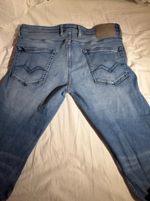 Ljusblå Replay jeans straight fit- inga slitage - Ljusblå jeans från Replay med raka ben och klassisk femficksdesign. Snygga detaljer på bakfickorna och ett Replay-läderpatch i midjan. Jeansen är tillverkade i mjukt bomullsjeans och har en avslappnad passform som funkar till det mesta.