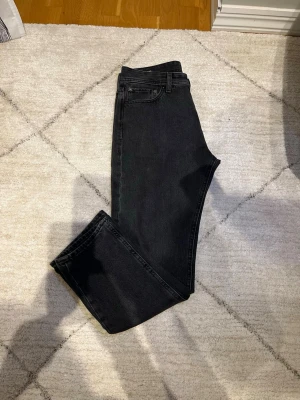 Svarta raka jeans från Jack & Jones - Snygga svarta jeans från Jack & Jones med klassisk femficksdesign och raka ben. Jeansen har en enkel look utan slitningar och passar perfekt till en avslappnad stil. Tillverkade i mjukt denimtyg för skön känsla hela dagen.