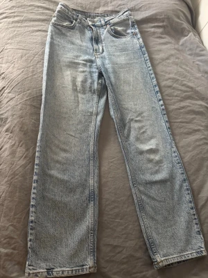Ljusblå raka jeans från BikBok - Säljer ett par ljusblå jeans från BikBok med klassisk femficksdesign och raka ben. Jeansen har en snygg tvättad look och är tillverkade i bomullsdenim. Perfekta för en avslappnad och trendig stil.