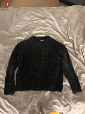 Svart chenilletröja  - Mysig svart stickad tröja i chenillematerial från Kappahl. Tröjan har rund halsringning, långa ärmar och ribbade muddar vid ärmslut och nederkant. Perfekt för kalla dagar och enkel att styla till olika outfits.