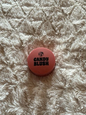 W7 Candy Blush rouge rosa - Ett kompakt rouge från W7 i serien Candy Blush. Färgen är en söt rosa nyans och förpackningen är rund och smidig i plast. Perfekt för att ge kinderna en fräsch och ungdomlig look.