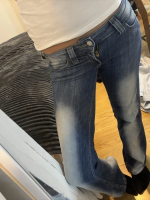 Blå bootcut jeans med låg midja - Säljer ett par skit snygga blå bootcut,lowwaist jeans med  snygga slitningar framtill. Jeansen har klassisk femficksdesign och dragkedja från Weekday-cheap Monday 
