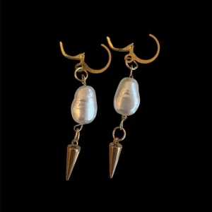 Guldörhängen med pärlor och spikes - Unika örhängen i guldton med oregelbundna vita pärlor och coola konformade spikes. Snygg kombination av klassiskt och edgy stil, perfekta för att sticka ut. Hängande modell med guldfärgade detaljer och pärlor som ger en lyxig känsla.OBS, Endast öronhångena på första bilden i andra bilden visar det i perspektiv till våra andra smycken💕