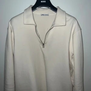 Vit half zip tröja från Zara - Vit långärmad tröja från Zara med krage och halv dragkedja framtill. Tröjan har en clean och stilren look, tillverkad i mjuk bomull. Perfekt för dig som gillar minimalistisk stil och vill ha något enkelt men snyggt.