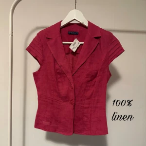 Rosa linneskjorta från Blue Sand - Snygg rosa skjorta från Blue Sand i 100% linne. Skjortan har korta ärmar med veckade detaljer, klassisk krage och knäppning framtill med två knappar. Figursydd modell som ger en clean och fräsch look. Perfekt för dig som gillar stilrena plagg med twist. Köpt för 250kr och säljer för lite billigare. 