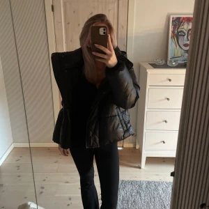 Svart pufferjacka med hög krage - Säljer en jättesnygg svart pufferjacka med hög krage och quiltad design. Jackan är kortare i modellen och har en oversized passform. 