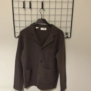 Brun ullkavaj från Selected Homme - Mörkbrun kavaj i ull från Selected Homme. Klassisk design med tre knappar framtill, två stora fickor och en bröstficka. Mjuk och lite ruggad yta, perfekt för lager-på-lager under höst och vinter. Snygg och enkel att styla till det mesta. Använd vid fåtal tillfällen så i nyskick.