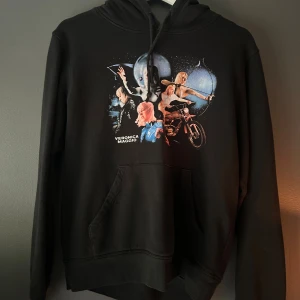 Svart Veronica Maggio hoodie med tryck - Svart hoodie med coolt färgstarkt tryck framtill som visar olika motiv och texten 'Veronica Maggio'. Kommer ej till användning. Står både att det är en storlek S och XS men skulle säga att den är mera som en XS då den är liten i storleken😋😋