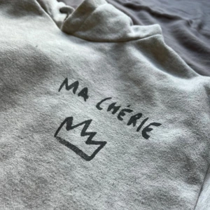 Grå hoodie med tryck 'Ma Chérie' - Grå hoodie med mörkgrå tryck 'Ma Chérie' och en krona både fram och bak. Köpt på Gina tricot. Perfekt för en chill och avslappnad stil.
