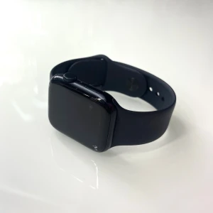 Svart Apple Watch med silikonarmband - Snygg svart Apple Watch med fyrkantig urtavla och mjukt silikonarmband. Klockan har en stilren digital display och passar perfekt för dig som gillar teknik och smarta funktioner. Enkel att justera med flera hål i armbandet. Apple Watch SE 2nd Gen 44mm GPS (Midnight Alu/Midnight sportband M/L)