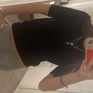 Svart croppad topp från Zara - En stilren svart croppad topp från Zara med rund hals och korta ärmar. Toppen har en enkel och clean look som är lätt att matcha med olika outfits. Mjuk och skön kvalitet, perfekt för dig som gillar minimalistisk stil.