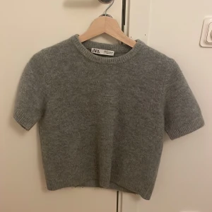 Grå stickad kortärmad tröja Zara - Mysig grå stickad tröja från Zara med korta ärmar och rund hals. Den är storlek M men passar mig jättebra som brukar ha S och XS. Använd några få gånger men inga fläckar eller tecken på användning. Skickar inom 1-2 dagar. Priset kan diskuteras.