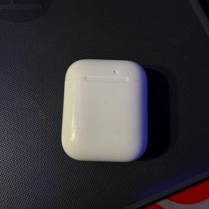 Apple AirPods (2nd generation) - Säljer ett par Apple AirPods (2nd gen) med laddningsetui. Fungerar utmärkt, synligt bruksslitage på etuiet men hörlurarna är i gott skick. Perfekt för trådlös musik och samtal. Laddningsindikatorn fungerar. Levereras rengjorda och redo att användas.