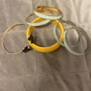 Mix av armband och örhängen i silver och gult - Säljer ett set med stora glittriga silverfärgade hoops, ett gult chunky armband och ett smalt guldfärgat armband med svarta fjärilar. Perfekt för dig som gillar att mixa färger och former i din stil.