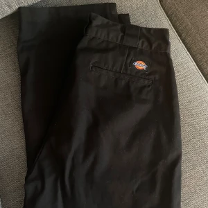 Dickies kostymbyxor - Svarta vintage byxor från Dickies med klassisk logga ovanför bakfickan. Raka ben, breda hällor och sidofickor. Snygg och enkel design i slitstarkt material, perfekta för en clean streetstil. 