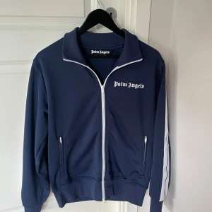 Palm Angels tröja/zip - Säljer min Palm Angels tröja/zip då den blivit för liten för mig. Storlek M.  Stilren tröja som passar till det mesta. Tröjan är i väldigt bra skick. Äkthets bevis finns. Köpt för 2,5/3 år sedan. Nypris runt 3500 kronor. Hör gärna av er vid frågor. 