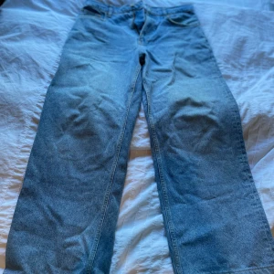 Blå jeans från Woodbird, storlek 30/30 - Säljer ett par klassiska blå jeans från Woodbird i modellen 'Slim Store'. Jeansen har en rak passform och är tillverkade i autentiskt blått denimtyg av bomull. Perfekta för dig som gillar en enkel och stilren look.