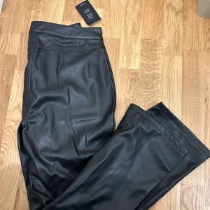 Svarta skinnbyxor från NA-KD - Snygga svarta skinnbyxor från NA-KD. Byxorna har klassisk design med knapp och dragkedja framtill. Perfekta för dig som vill ha en edgy look med stilren känsla.