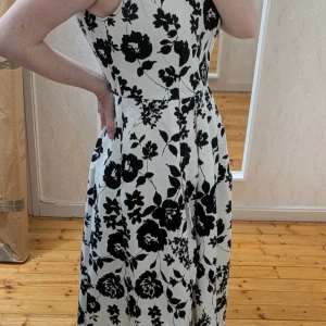 Vit och svart blommig långklänning Tu - Supersnygg långklänning från Tu Premium Collection i vit med svart blommigt mönster. Klänningen är ärmlös med v-ringning både fram och bak, markerad midja och lätt utställd kjol. Materialet är strukturerat och känns lyxigt. Perfekt för dig som vill sticka ut. - White dress with black flowers  - Size 10 (38) - Big in size - Length 155cm - I think I only wore it one time to a wedding reception. - Has pockets - Thick fabric - Zip at back - 98% cotton