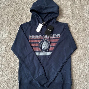 Ysl Saint Laurent hoodie - Säljer denna riktigt snygga Saint Laurent hoodie i storlek S och i skick 10/10! Hoodien är köpt på vinted med authentic lable. Orginal pris - 8000kr Vårat pris - 1799kr! Priset är ej hugget i sten🙌Skriv vid minsta lilla fundering🙌