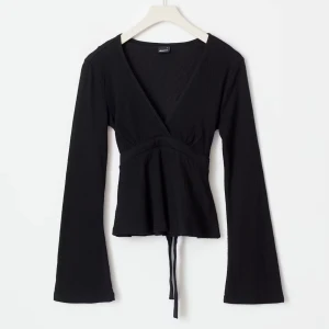 Tie top Svart Gina tricot - Svart topp från Ginatricot med v-ringning och långa utsvängda ärmar.🤩 Toppen har knytband i midjan och har används 3-4 gånger.💕 Säljer då jag tycker att den är lite för liten för mig. Nypris var 300kr