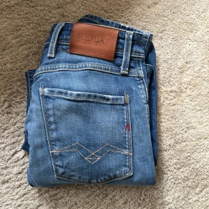 Replay Anbass jeans slim fit - Säljer ett par Replay Anbass jeans med snygga slitningar och klassiska detaljer. Slim fit-modell, läderpatch bak och diskret Replay-logga. Perfekta för dig som gillar en modern och stilren look. Skick 9/10 använda fåtal gånger. Storlek 27/30. Kontaka för mer frågor 