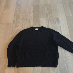 Svart stickad tröja från Pure Friday - En svart stickad tröja från Pure Friday i enkel och klassisk modell. Tröjan har rund halsringning, långa ärmar och ribbade muddar vid ärmslut och nederkant. Lite liten i storlek så skulle säga mer S än M 