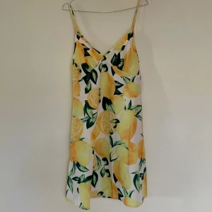 Somrig citronklänning - Fräsch kort klänning med citronmönster och smala axelband. 