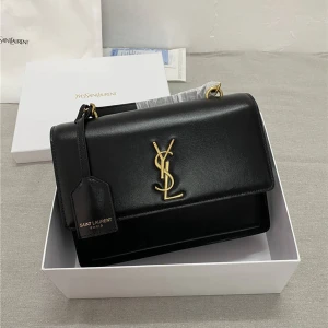 Svart axelväska från Saint Laurent - Snygg svart axelväska från Saint Laurent i slätt skinn med guldiga detaljer och ikoniskt YSL-emblem framtill. Väskan har en kedjerem i guld och ett elegant, stilrent uttryck. Perfekt storlek för det viktigaste och med klassisk design.