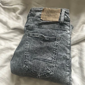 Gråsvarta Garcia straight jeans 152 - Säljer ett par gråsvarta Garcia jeans i straight fit med relaxed waist. Snyggt tvättad denim med klassiska fem fickor och tydliga sömmar. Modellen heter Ilyano Straight Fit och passar dig som gillar en rak och avslappnad look.