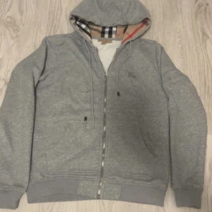 Grå hoodie från Burberry med dragkedja - Säljer en grå hoodie från Burberry med klassiskt rutigt foder. Säljer för den e lite liten på mig tycker jag. Den är inte original om du kopplar! Skriv gärna om du undrar något😃