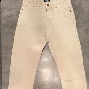 Beige jeans Relaxed Chris Jack & Jones - Beiga jeans från Jack & Jones, modell Relaxed Chris. Klassisk femficksdesign med avslappnad passform och raka ben. Tillverkade i bomull för en skön känsla. Perfekta för dig som gillar en loose och chill stil.