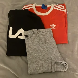 Nike hoodie i grått och svart - Nike hoodie i grått och svart med stor vit logga på bröstet. Tröjan har huva med snörning och en stor magficka. Perfekt för chill dagar eller när du vill ha en sportig look. Långärmad och i mjukt material. Beställning tillsammans med en grå klänning, långärmad Adidas tröja och en svart fila hoodie.