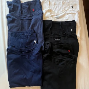 Polo Ralph Lauren t-shirts i olika färger botten logo - Säljer flera klassiska t-shirts från Polo Ralph Lauren i svart, marinblått och vitt. Alla har den ikoniska broderade loggan på nedre kant . T-shirtsen är kortärmade och gjorda i mjuk bomull, perfekt för en clean och stilren look.