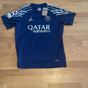 PSG Barcola 29 matchtröja Jordan M - Paris Saint-Germain fotbollströja med Barcola 29-tryck, tillverkad i lätt och ventilerande material. Djupblå färg med vita detaljer, Jordan-logga och Qatar Airways sponsortryck. Snygga mönstrade axelpartier och klassisk passform.