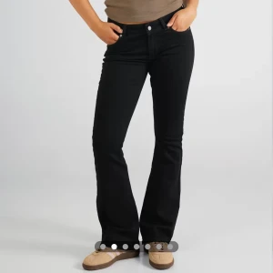 Svarta bootcut jeans från Junkyard - Svarta jeans från Junkyard med klassisk femficksdesign och bootcut-silhuett. Jeansen har normal passform, midwaist och är tillverkade i ett stretchigt bomullsmaterial för extra komfort. Perfekta för dig som gillar en tidlös look med lite utsvängda ben.