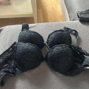 Svart spets-bh från Lindex Alva 70B - Säljer en svart bh från Lindex Alva i storlek 70B. Bh:n är täckt av vacker spets med blommigt mönster och har tunna axelband. Materialet är mjukt och bekvämt, tillverkat med återvunnen polyamid. Perfekt för dig som gillar stilrena och eleganta underkläder.