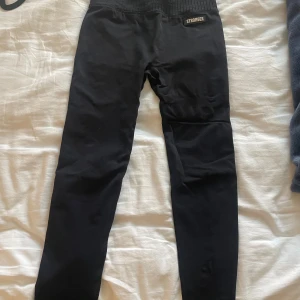 Svarta träningstights  - Svarta träningstights från Stronger strl XS. Använda men i fint skick. Har detalj på vänstra låret