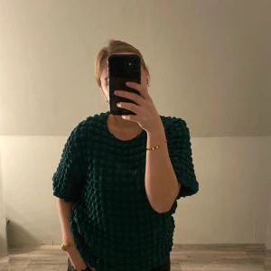 Grön tröja Rut&Circle S - Unik mörkgrön tröja från Rut&Circle i storlek S. Tröjan har en cool bubblig struktur, rund hals och korta ärmar. Den är perfekt för dig som vill sticka ut med en trendig look.