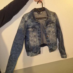 Jeansjacka - Snygg jeansjacka från H&M i tvättad blå denim. Klassisk modell med bröstfickor, metallknappar och långa ärmar. Perfekt för dig som vill ha en cool och tidlös look.
