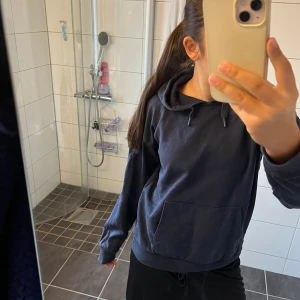 Mörkblå hoodie med huva och ficka - En basic mörkblå hoodie med huva och dragsko, samt en stor magficka framtill. Tröjan har långa ärmar och ribbade muddar vid ärmslut och nederkant. Perfekt för chill dagar eller när du vill ha något bekvämt och stilrent. Tröjan är i storlek 152 men har även en exakt likadan i 164. Skriv om ni vill köpa den i 164, samma pris och båda är endast använda ett fåtal gånger!💞