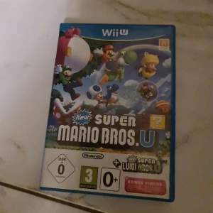 New Super Mario Bros. U (Wii U) - New Super Mario Bros. U till Wii U i fint skick. Inkluderar bonusinnehåll med New Super Luigi U. Omslaget och fodralet är hela och utan synliga skador. Perfekt för Mario-fans och familjespel. Passar alla åldrar från 3 år.