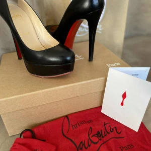 Christian Louboutin Bianca svarta pumps - Ikoniska svarta pumps från Christian Louboutin ”Bianca” med klassisk röd sula och hög klack. Skorna har rund tå och plattform, tillverkade i skinn. Perfekta för dig som vill sticka ut med en lyxig och tidlös look.
